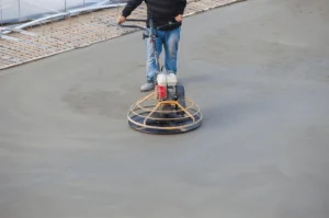 Concrete flatwork contractor operating a power trowel to smooth and finish a commercial slab